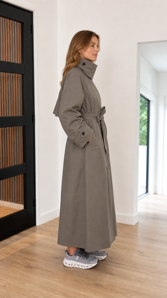 Side profile view of taupe belted full-length trench coat