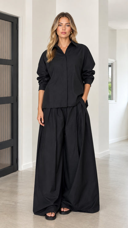 Front full view of women's relaxed two-piece set in black featuring collared shirt and wide-leg trousers