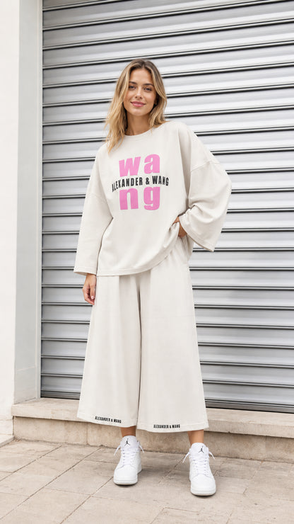 Front view of model wearing cream oversized graphic sweatshirt and wide leg cropped lounge pants set