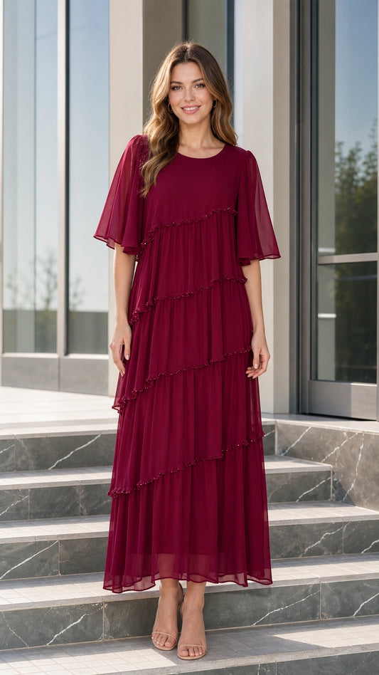 Front view of woman wearing burgundy tiered chiffon maxi dress with flutter sleeves