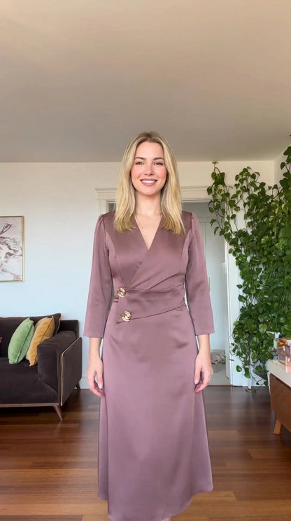 Front view of model wearing dusty mauve satin wrap-style maxi dress with gold buttons