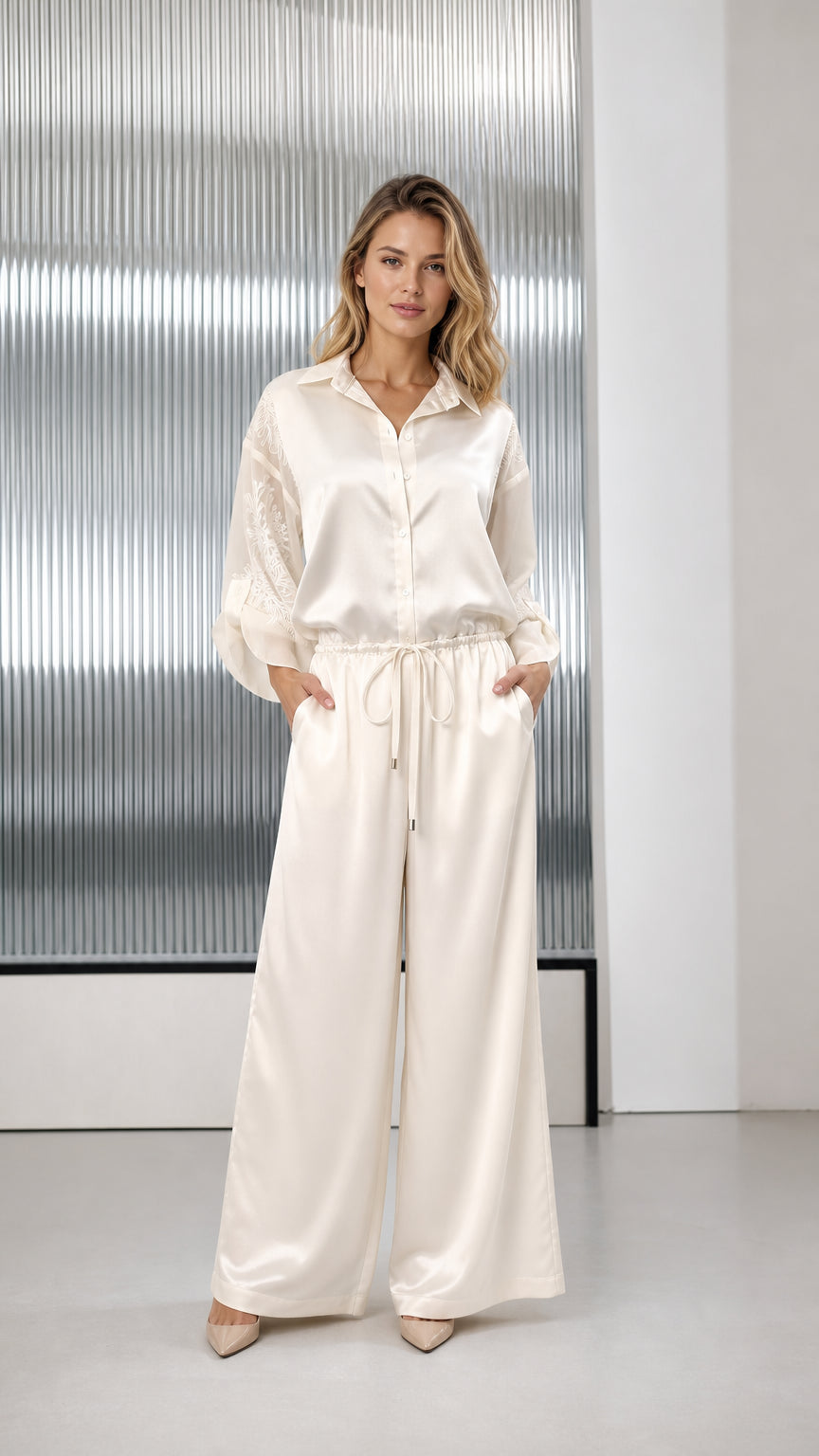 Front view of woman wearing ivory satin wide-leg jumpsuit with embroidered sleeves