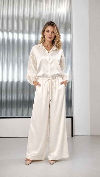 Front view of woman wearing ivory satin wide-leg jumpsuit with embroidered sleeves