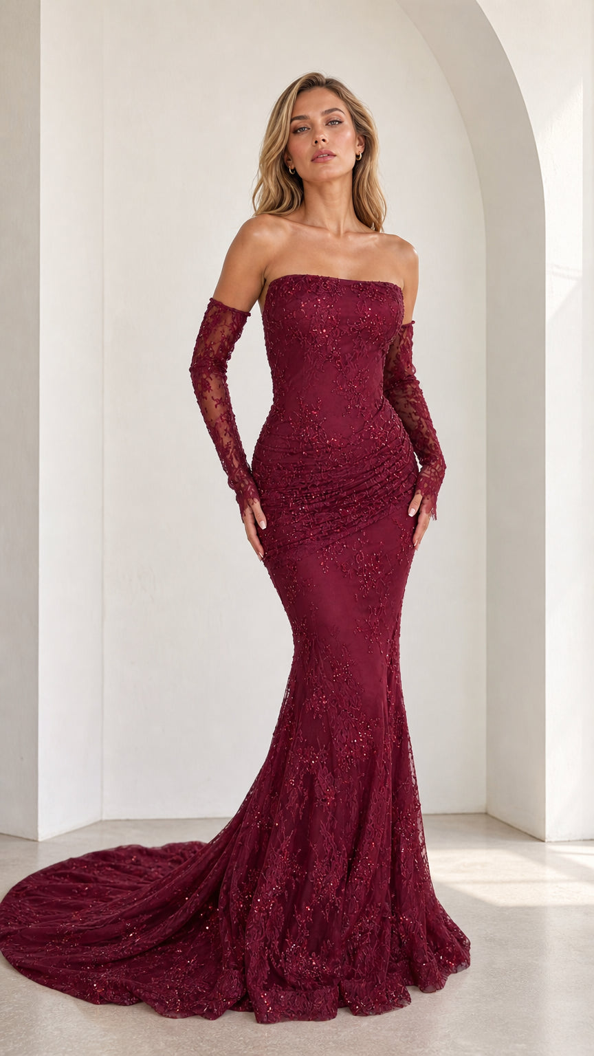 Front view of burgundy strapless beaded lace mermaid gown with sheer lace sleeves
