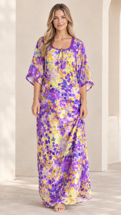 Front view of model wearing purple and yellow floral kaftan maxi dress with crochet lace neckline