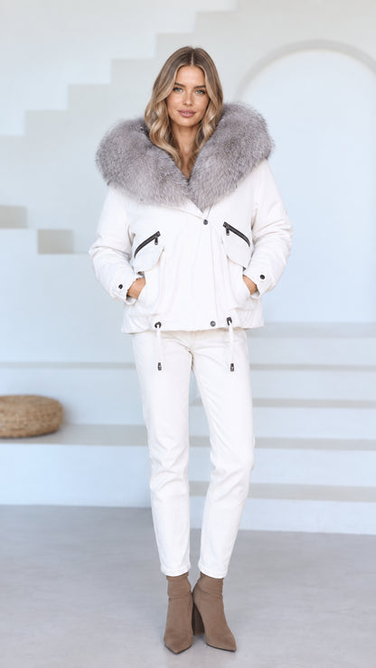 Front view of model wearing white hooded jacket with plush faux fur trim and matching white pants