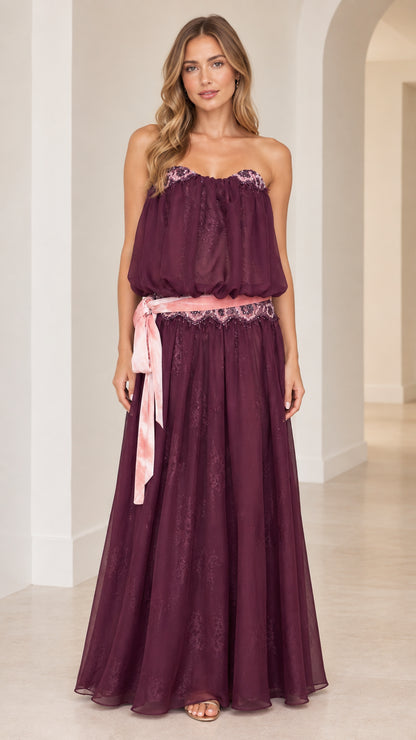 Front view of woman wearing strapless plum purple maxi dress with embroidered waist sash