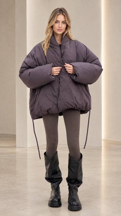 Front view of model wearing oversized slate purple bubble hem puffer jacket with tall black boots
