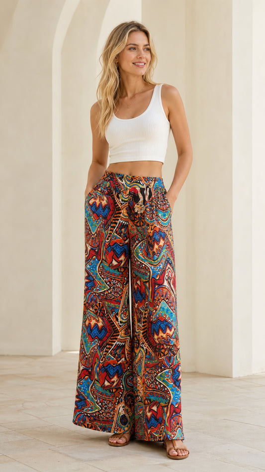 Front view of woman wearing vibrant rust multi bohemian wide leg pants with white crop tank