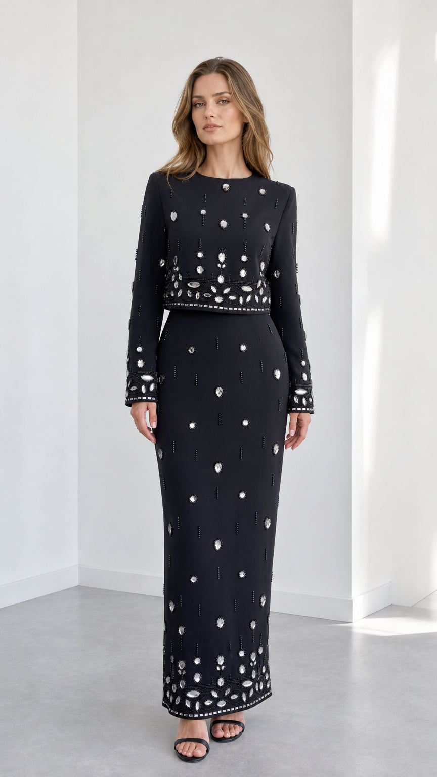 Front view of black long sleeve embellished crop top and column maxi skirt two-piece set