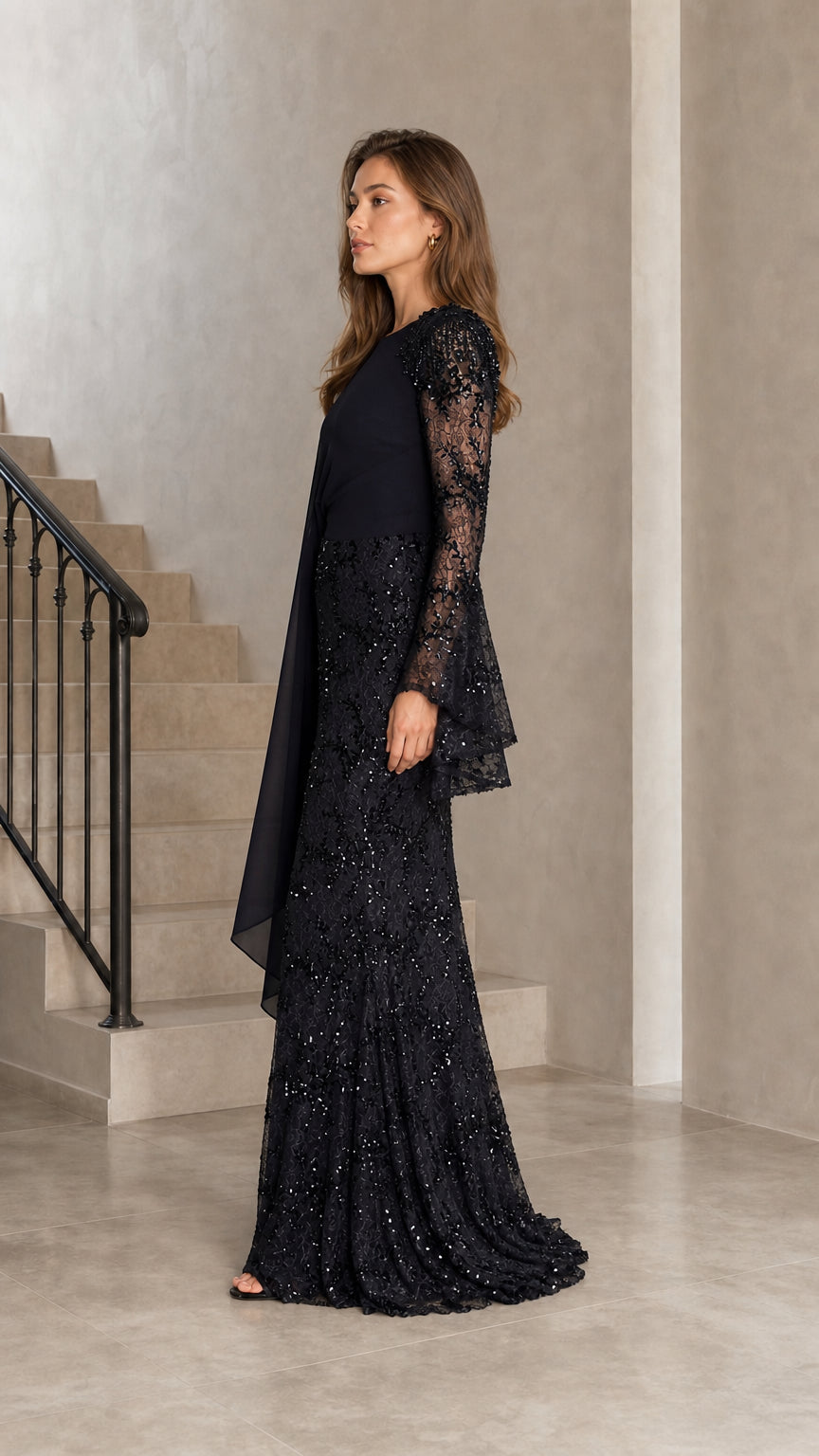 Side angle view of model in black long sleeve cape formal evening dress