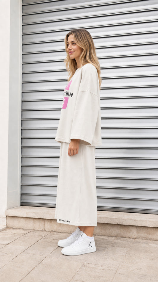 Side profile of model wearing cream two piece casual graphic sweatshirt and culotte set