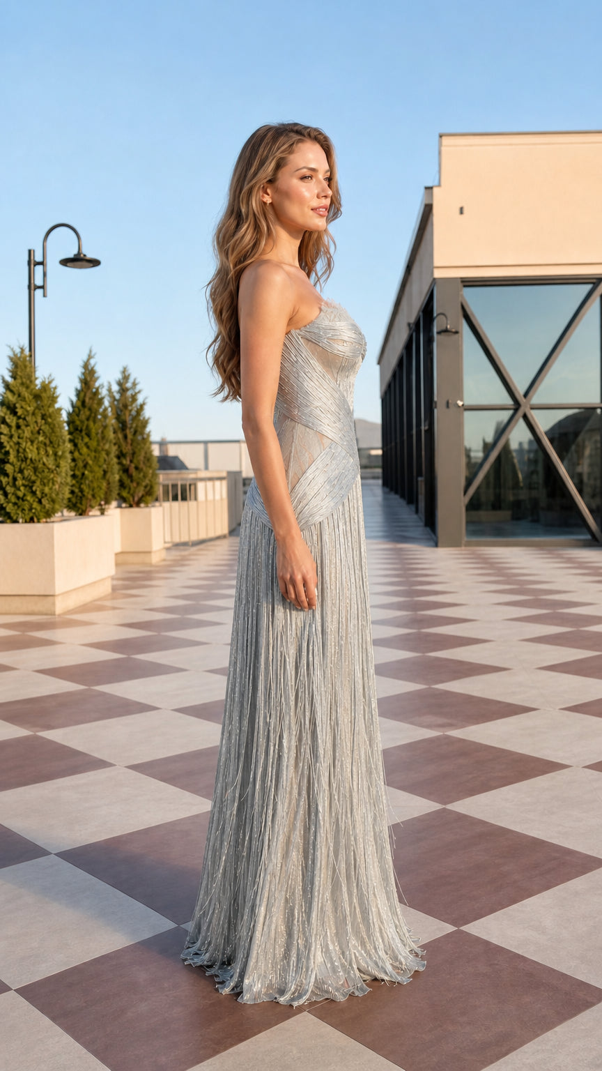 Side profile view of strapless silver fringe evening dress highlighting the structured bodice