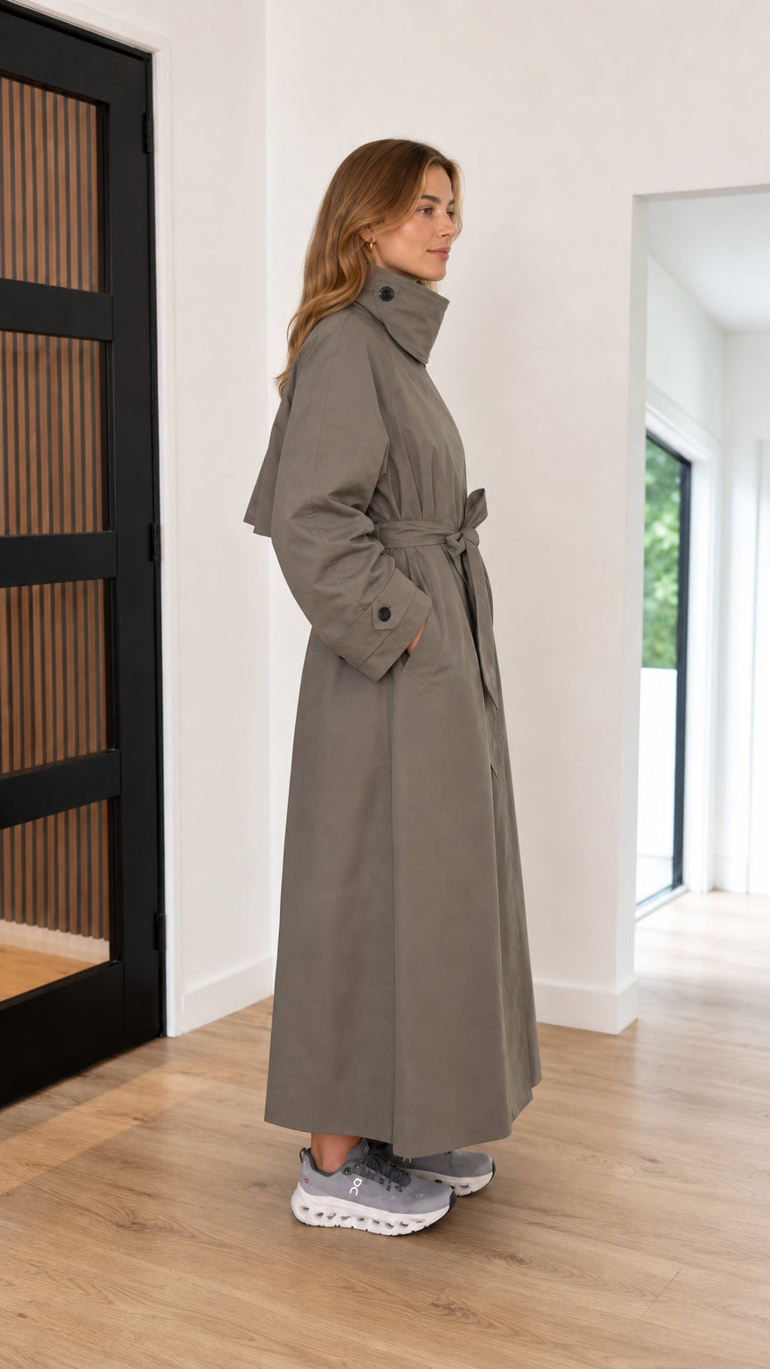Side profile view of taupe belted full-length trench coat