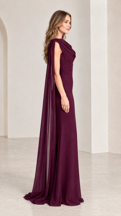 Side profile view of burgundy sleeveless formal gown with flowing cape