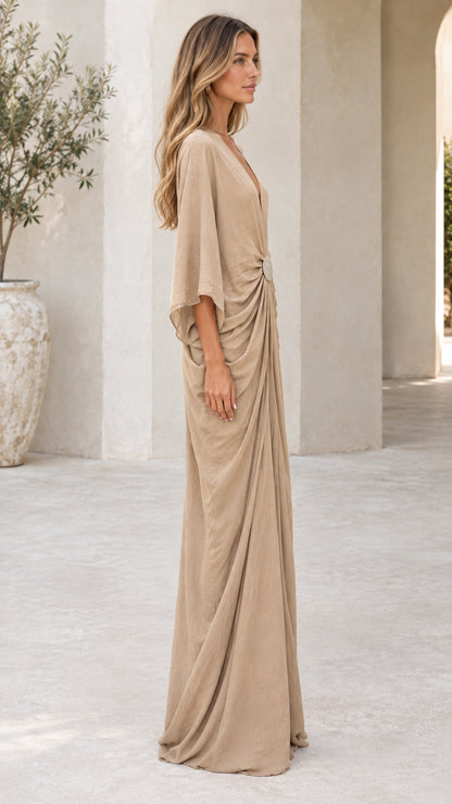 Side profile view of woman wearing beige draped kaftan maxi dress