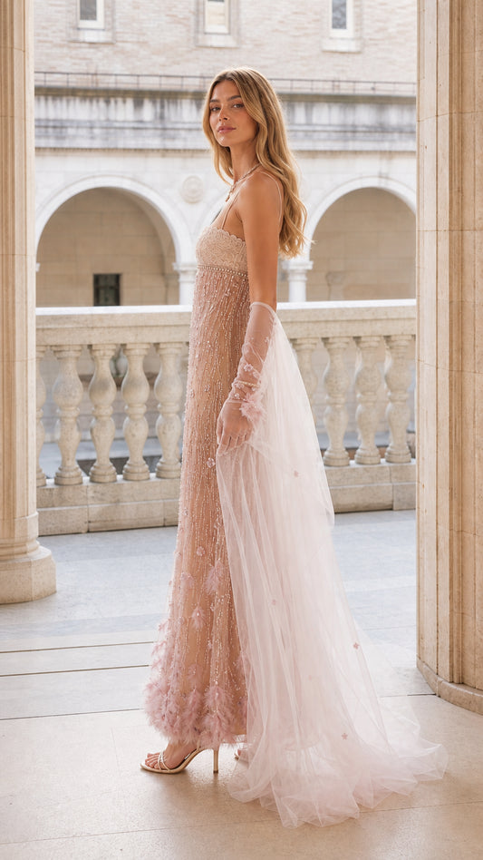 Side profile view of blush pink beaded evening gown with sheer cape