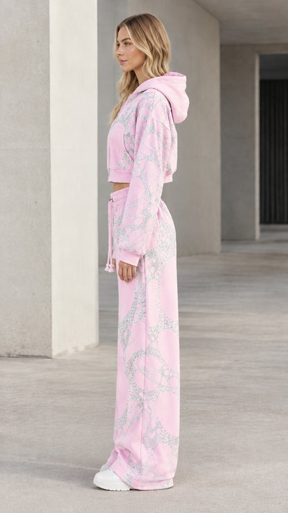 Side profile of model wearing pink cropped zip hoodie and matching wide-leg sweatpants