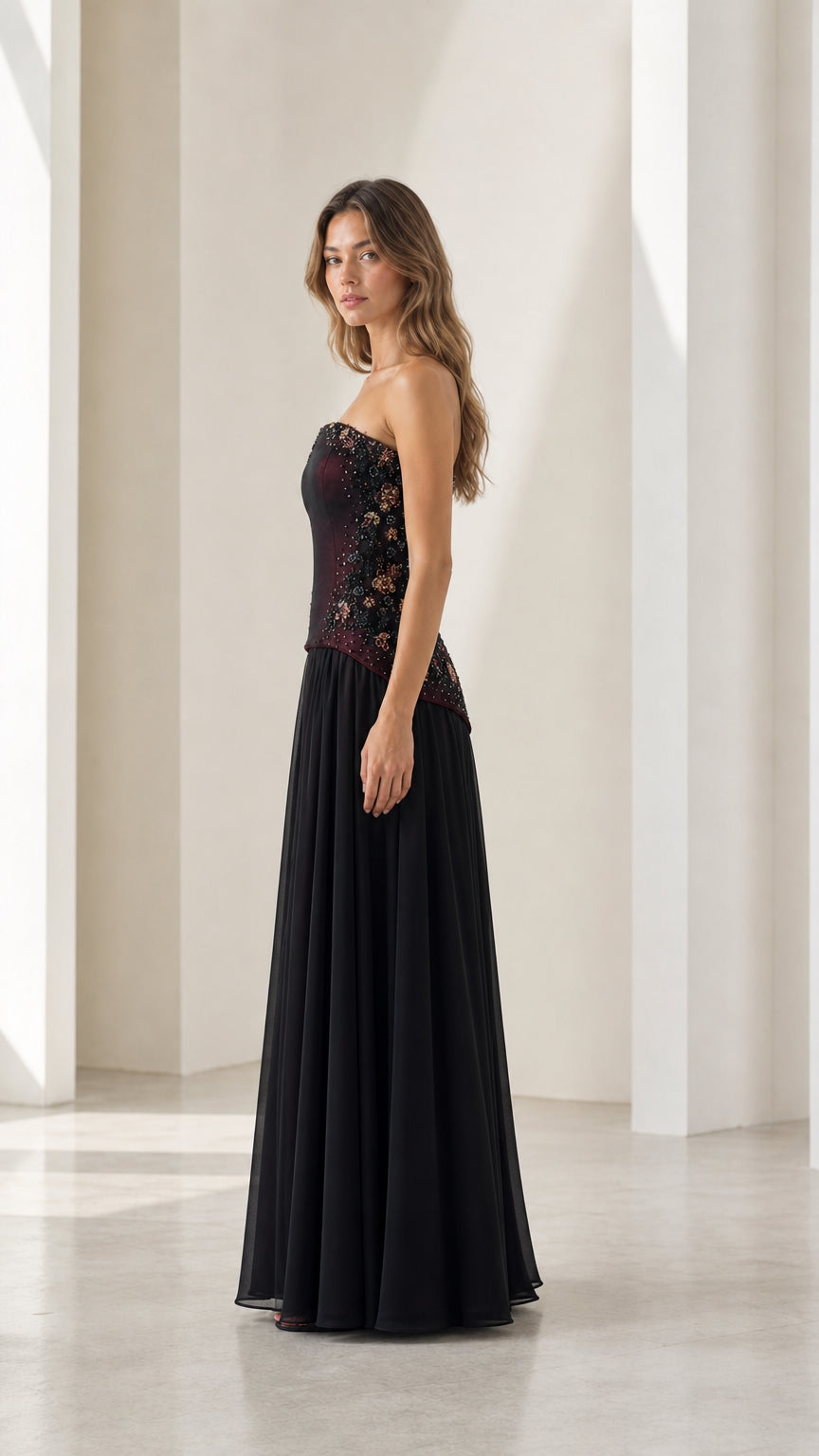 Side profile of burgundy formal gown with embellished bodice and pleated skirt