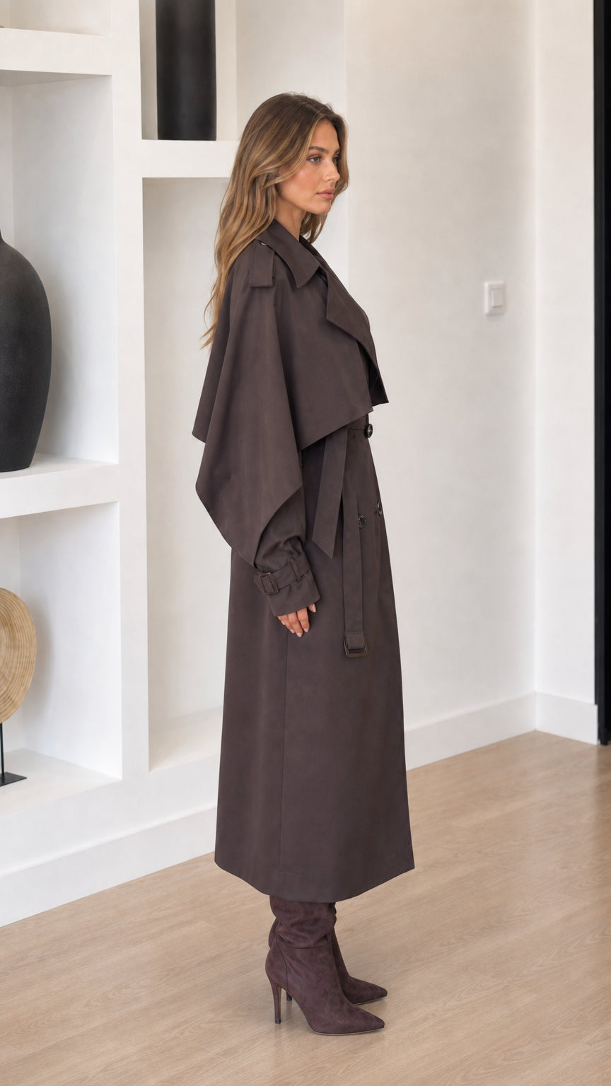 Dark brown women's trench coat shown from the side with layered shoulder detail