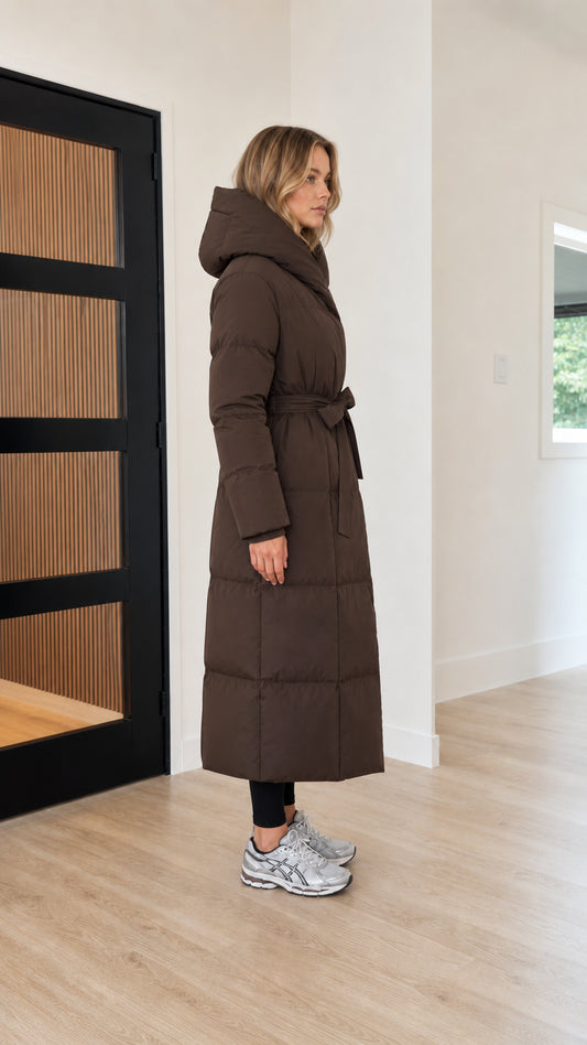 Side profile view of women's hooded long quilted puffer jacket in chocolate brown