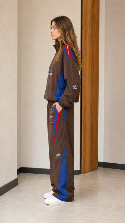 Side profile of woman wearing brown graphic windbreaker jacket and wide-leg track pants