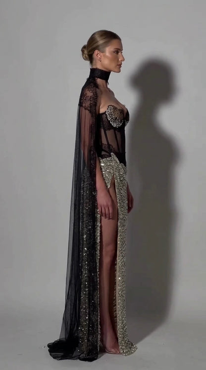 Side profile of model in silver sequin corset gown showing sheer back and floor-length cape