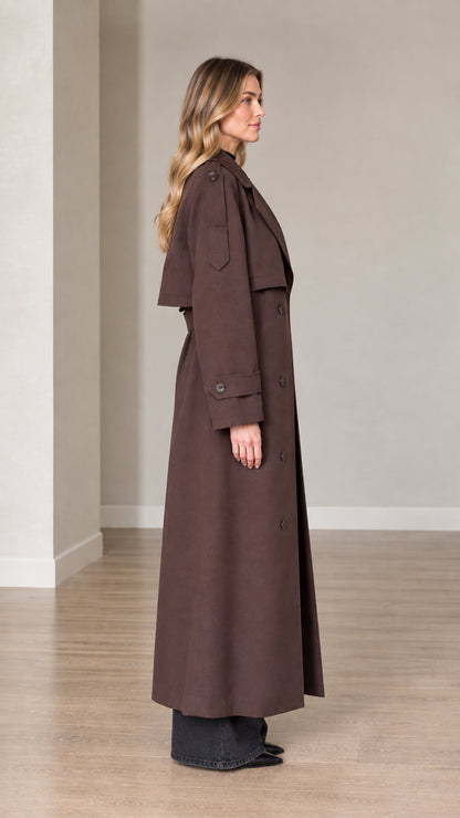 Side profile view of woman wearing brown maxi trench coat