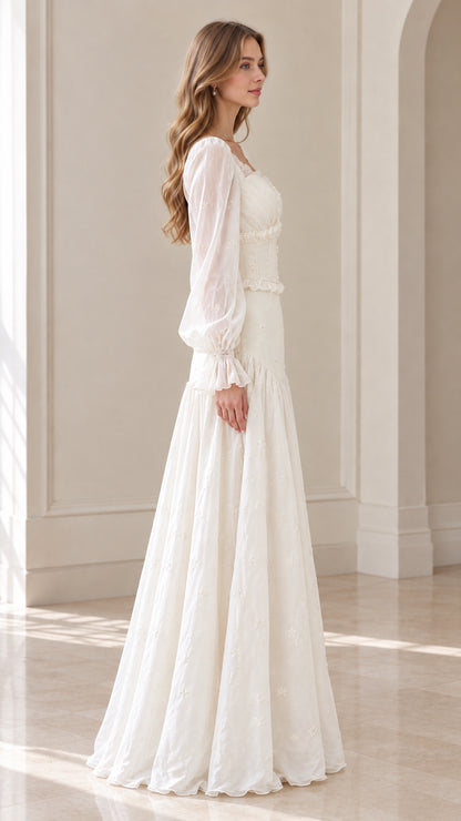 Side profile of model wearing ivory long sleeve embroidered maxi gown