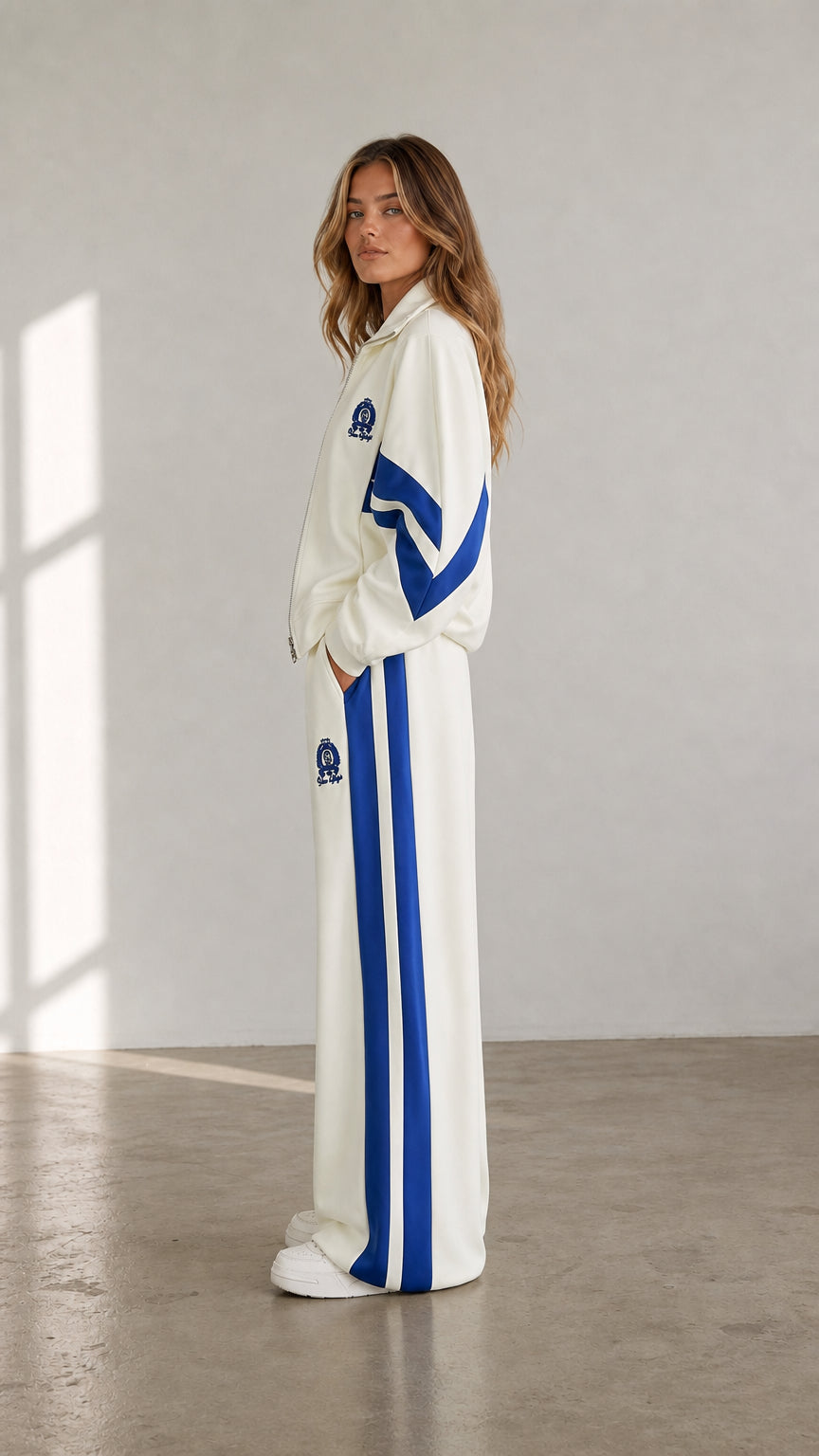 Side view of woman wearing cream wide-leg track pants and zip-up jacket