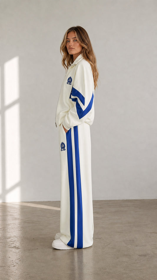 Side view of woman wearing cream wide-leg track pants and zip-up jacket