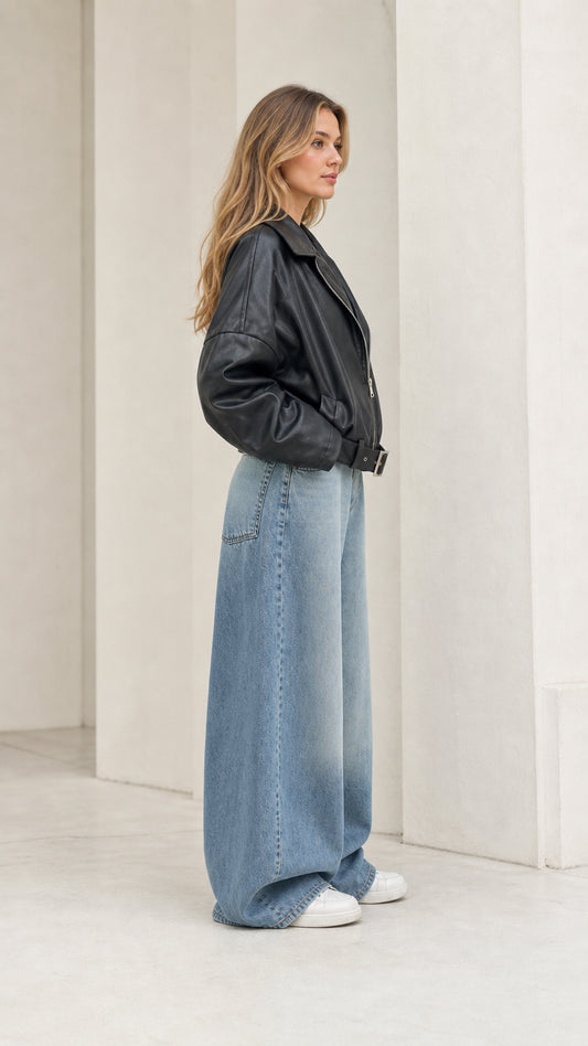 Side profile view of model wearing black faux leather bomber jacket