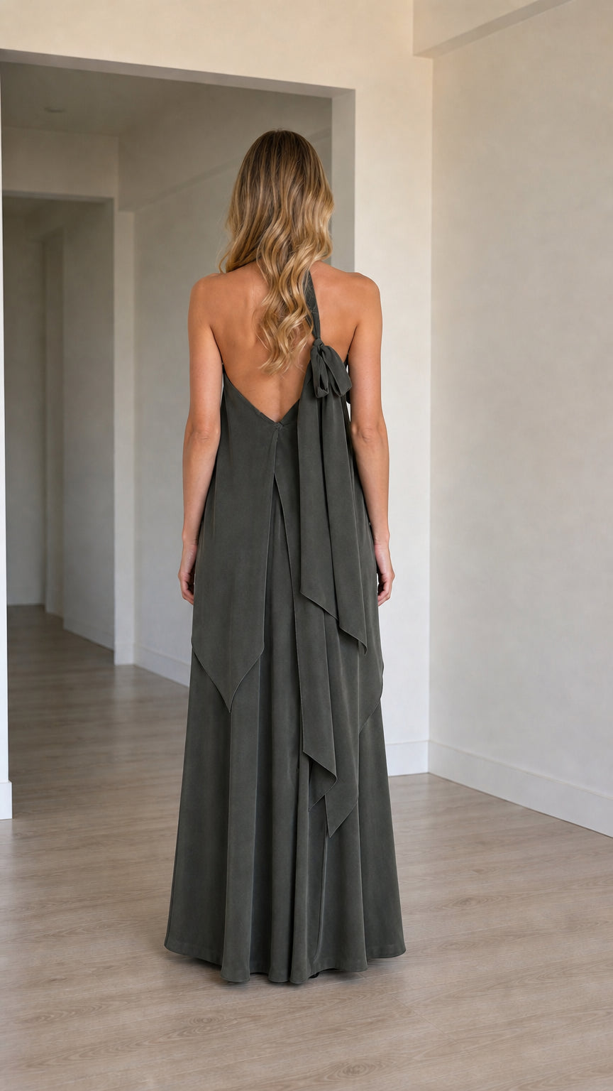 Back view of charcoal one-shoulder maxi dress showing low back and cascading shoulder tie