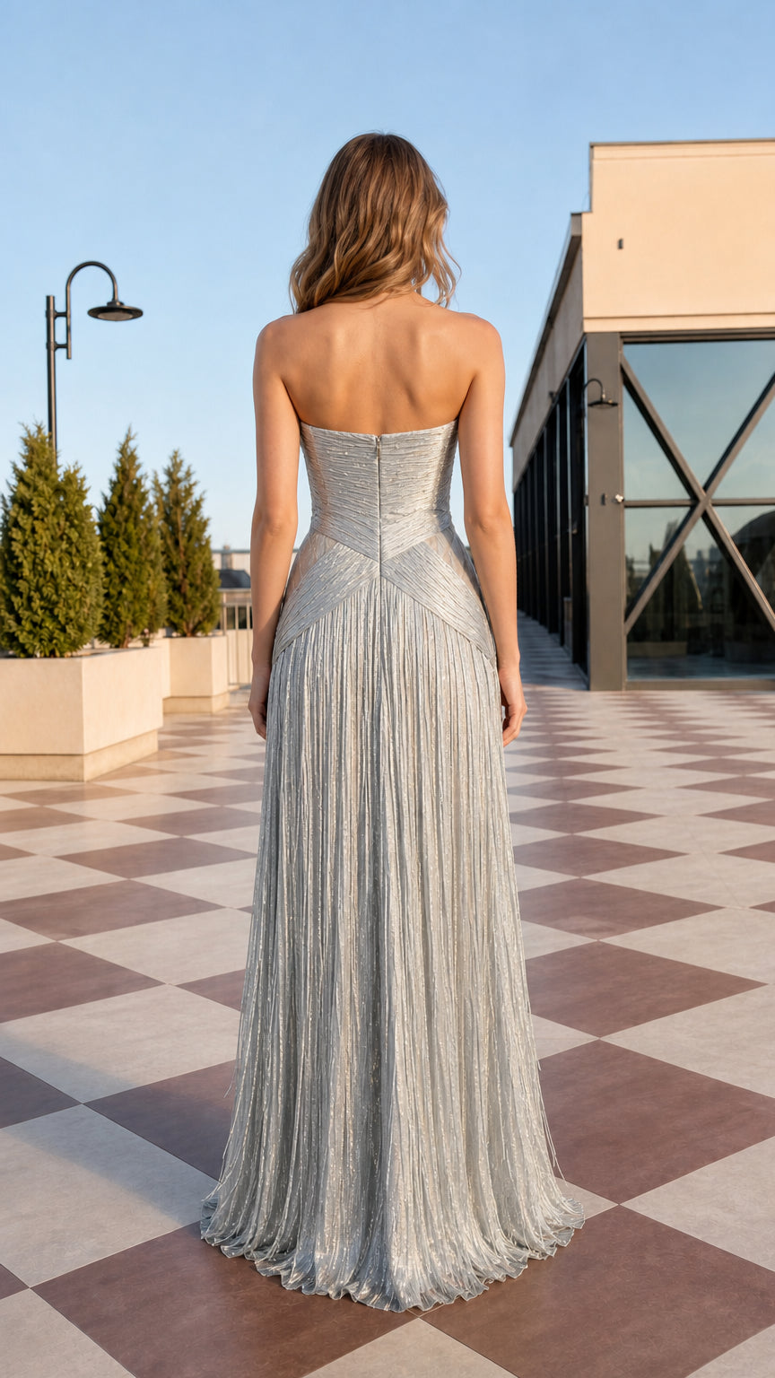 Back view of model in silver strapless floor-length evening gown with layered fringe