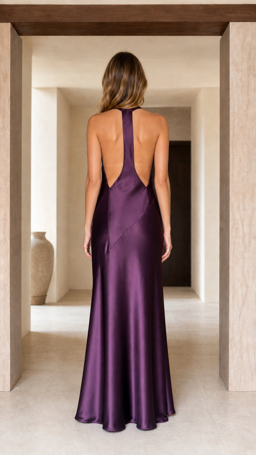 Back view of woman showing open back detail of plum purple satin halter dress