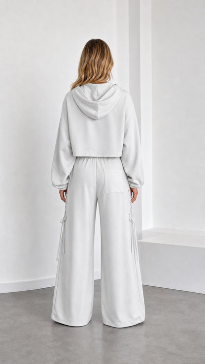 Back view of model in white oversized hooded crop shrug and wide leg sweatpants