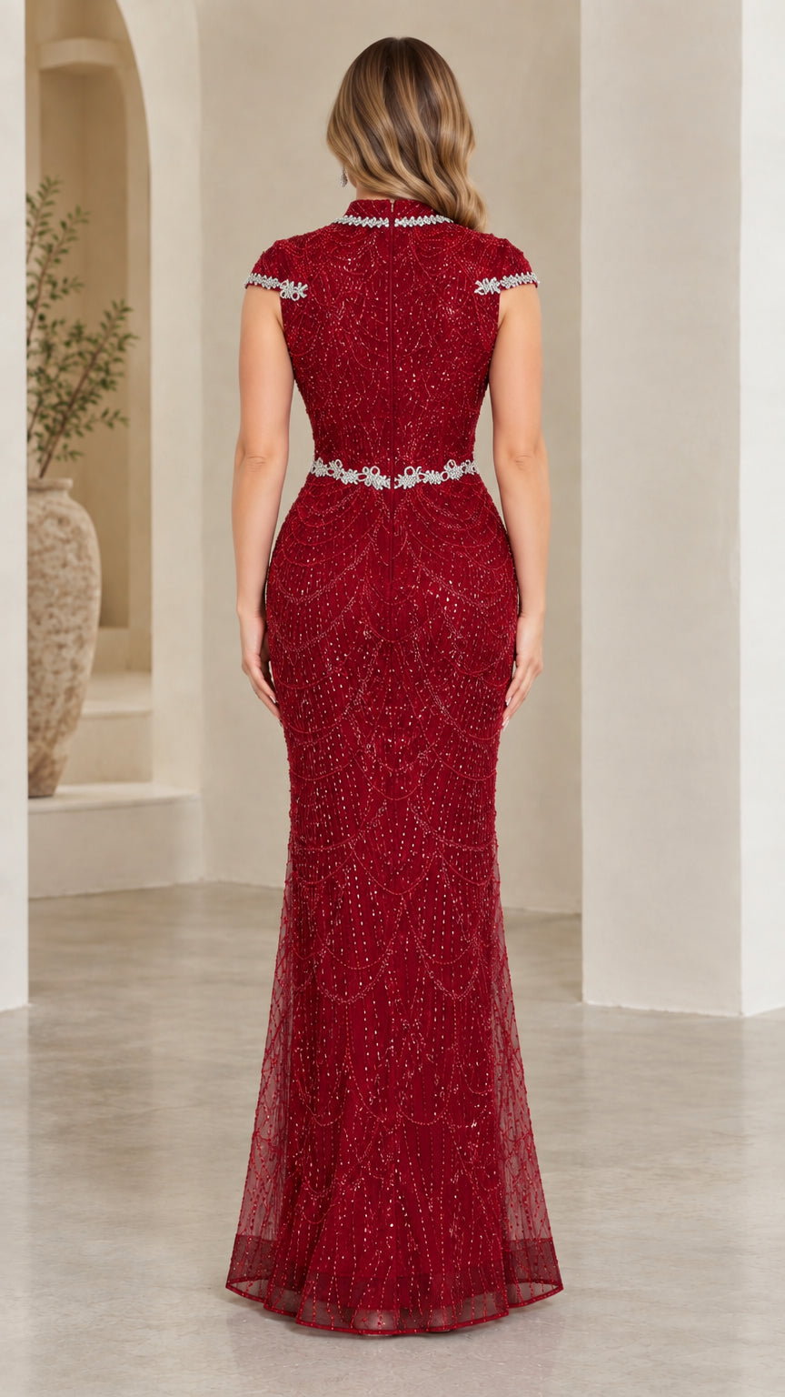 Back view of model in burgundy fitted mermaid gown with embellished trim