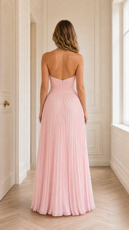 Back view of woman wearing open-back blush pink pleated maxi dress