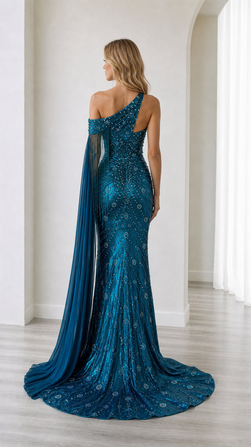 Rear view of the teal blue beaded mermaid gown showing the trailing sweep hemline and cape