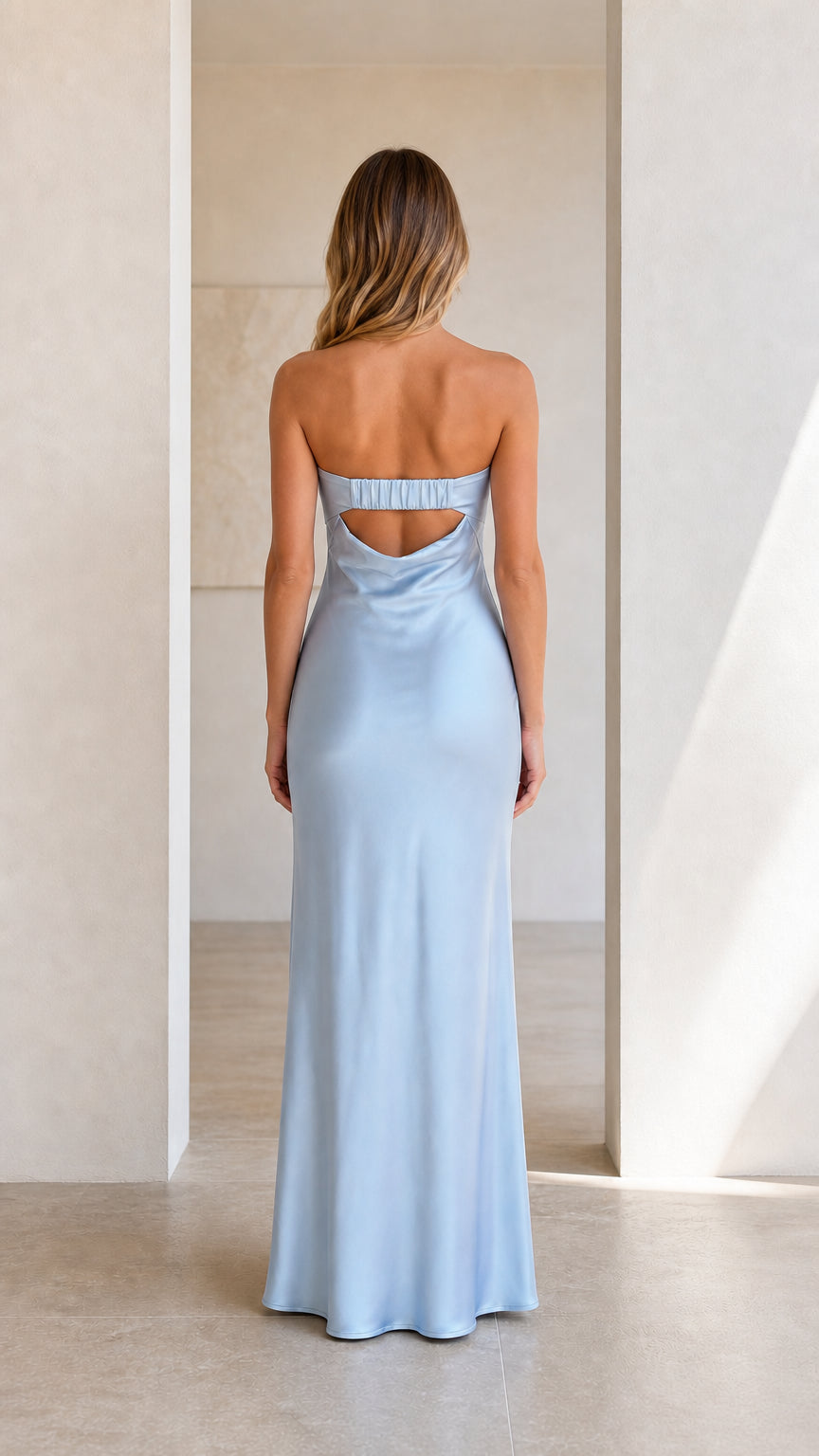 Back view of model in a light blue strapless satin dress showing back cutout