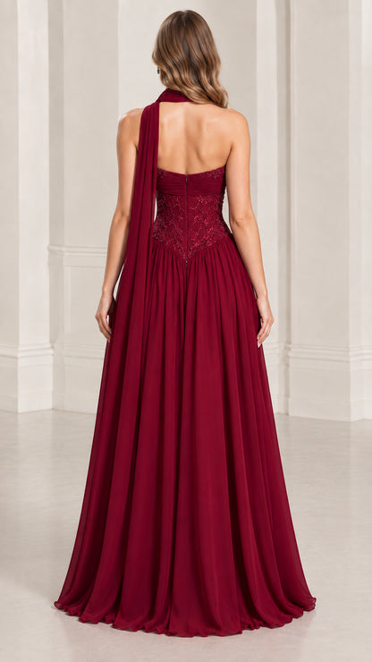 Back view of model showcasing flowing burgundy gown with back neck sash