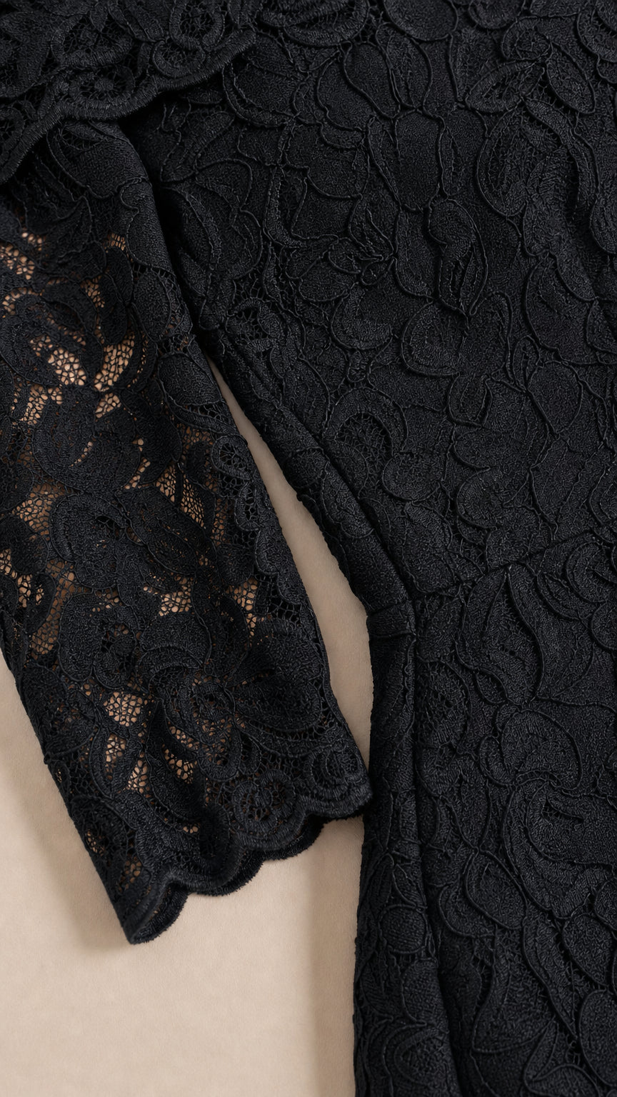 Close-up detail of textured black floral lace sleeve and scalloped cuff