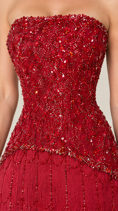 Close-up detail of sequin and bead floral embroidery on ruby red bodice and fringe waist