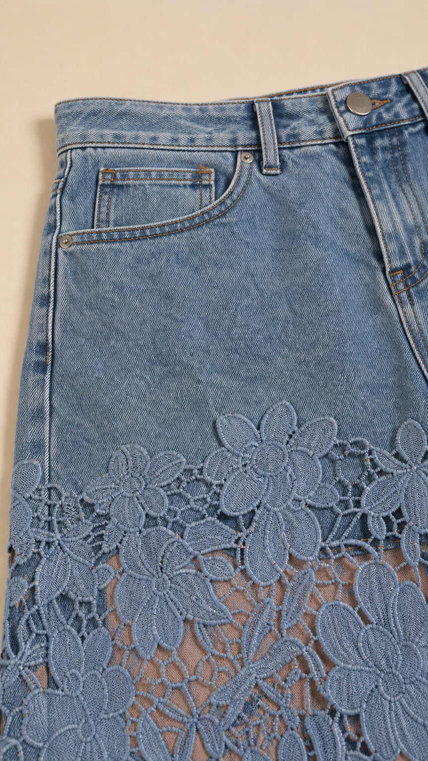 Close-up detail of denim pocket and delicate floral lace stitching