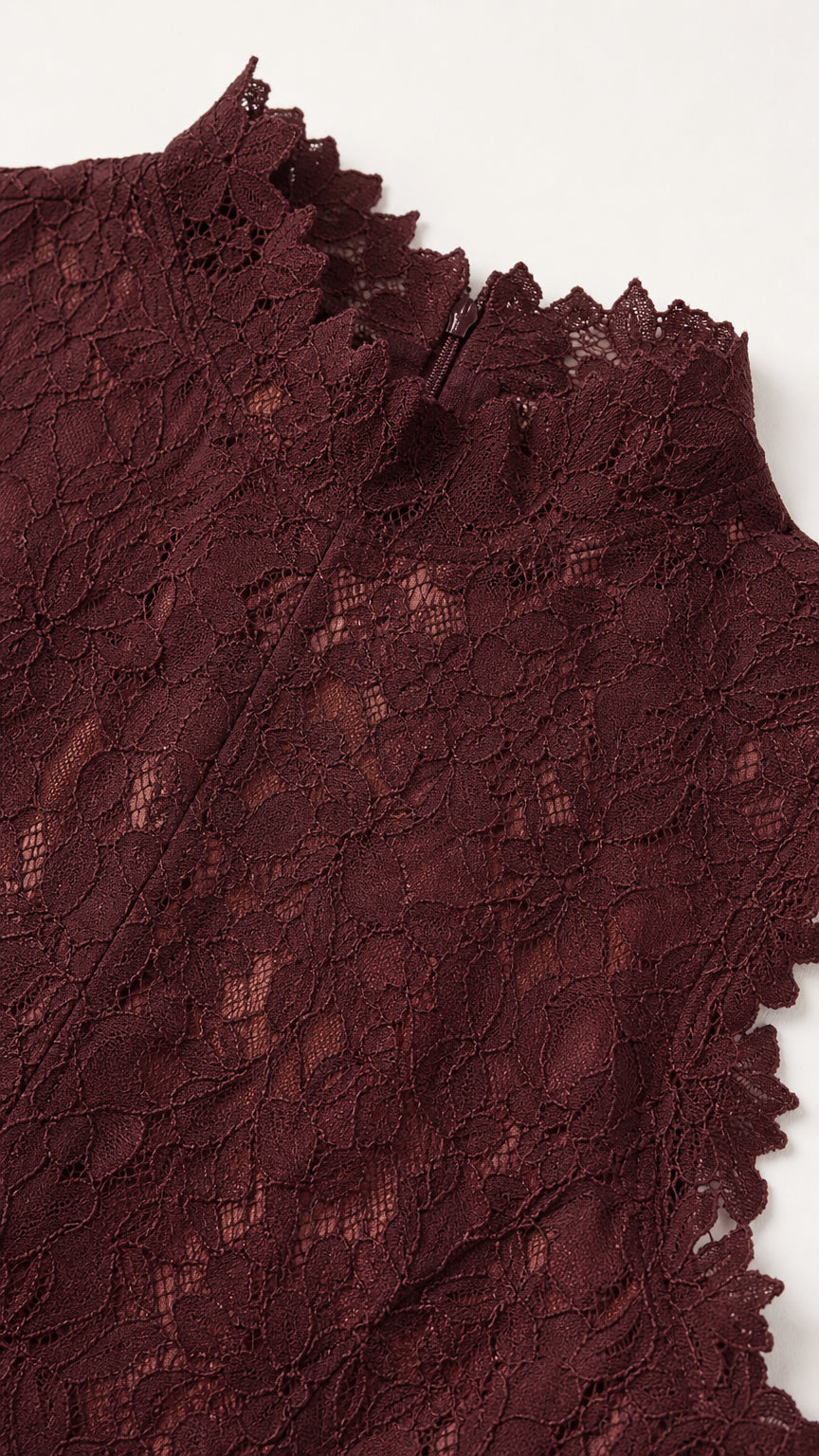 Close-up detail of burgundy floral lace texture and scalloped mock neckline