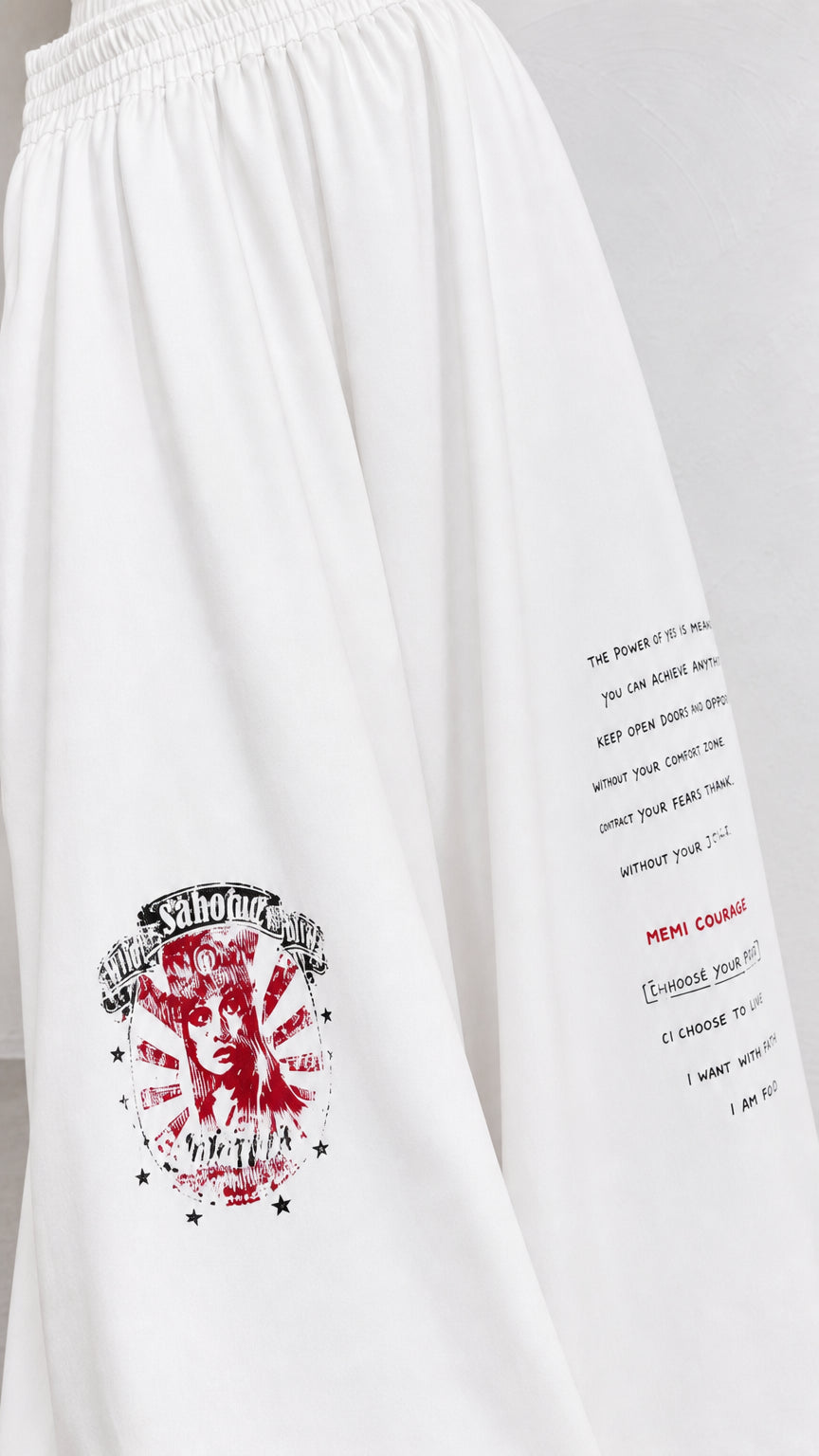 Close-up detail of white fabric, elastic waistband, and red graphic typography print