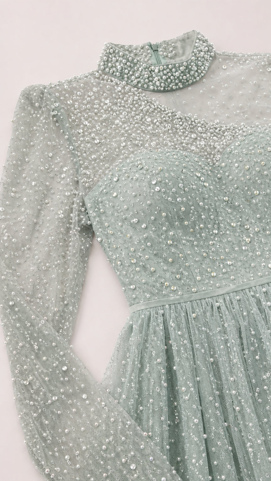 Close-up detail of high collar, pearl beading, and sheer illusion sleeve on evening dress