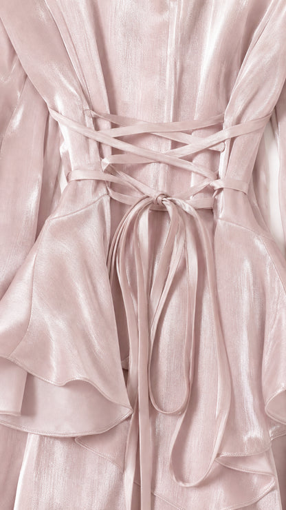 Close-up detail of the lace-up back and ruffled waist on pink dress