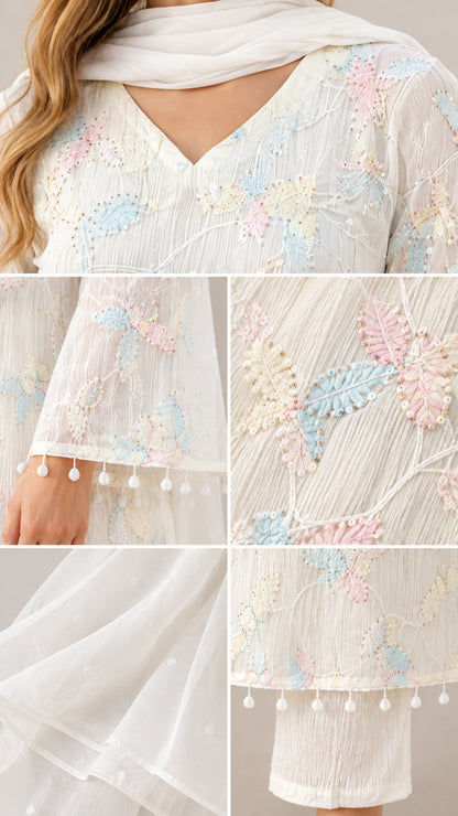 Close-up details of pastel floral embroidery, pom-pom tassel trim, and V-neckline
