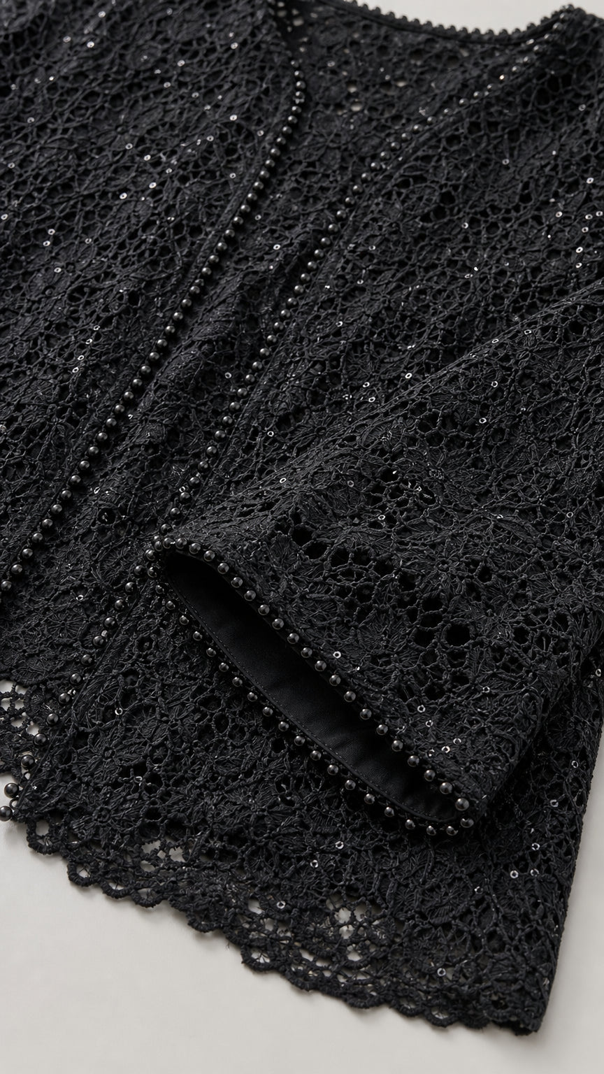 Close-up detail of delicate black floral lace fabric with beaded trim and sequins